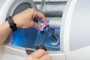 Person using CEREC machine to manufacture dental crown.